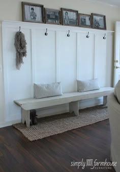 a white bench sitting in the middle of a living room next to a wall with pictures on it