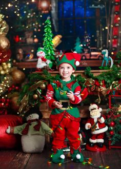 a little boy dressed up as santa clause standing in front of christmas decorations and presents