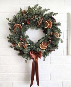 a wreath hanging on the wall with oranges and pine cones