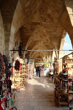 the inside of an outdoor market with lots of items on display and people walking around