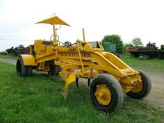 a yellow tractor parked on top of a lush green field