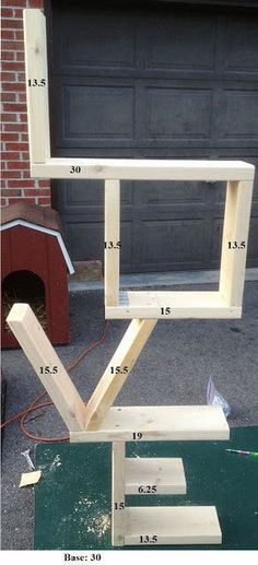 a wooden frame sitting on top of a table next to a dog house in the driveway