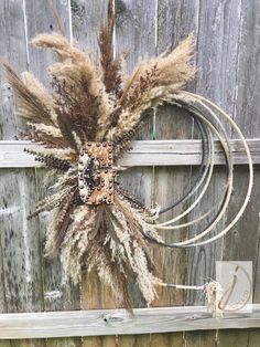 a wreath made out of dried grass on top of a wooden fence