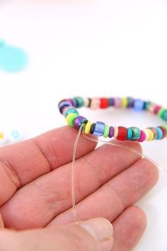 a hand holding a string with colorful beads on it