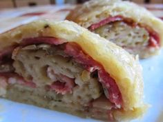 two pastries sitting on top of a white plate covered in meat and cheeses