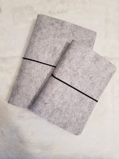 two gray notebooks sitting on top of a white blanket