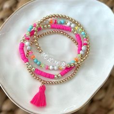 three bracelets with beads and tassels on a plate