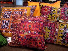 four colorful pillows on the floor in front of a fireplace