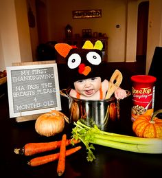 a baby in a chicken costume sitting in a pot with carrots and celery