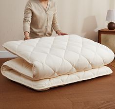 a woman standing next to two mattresses on the floor