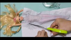 a barbie doll being cut by a person with scissors