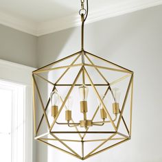 a chandelier hanging from the ceiling in a room with white walls and windows