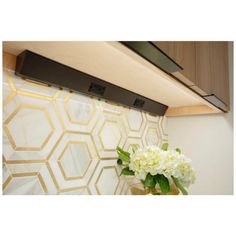 a vase filled with white flowers sitting on top of a counter next to a wall