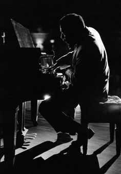 a man sitting at a piano in the dark