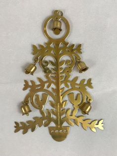 a gold metal christmas tree ornament with bells on it's back side