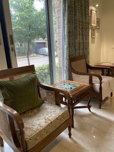 a living room with two chairs and a coffee table in front of a sliding glass door