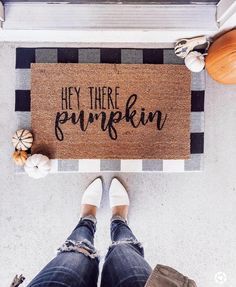 a person standing next to a door mat with the words hey there pumpkin on it