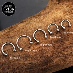 four pairs of nose piercings are shown on a piece of wood with the measurements for each