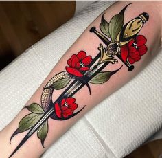 a tattoo on the arm of a woman with red flowers and two swords in it