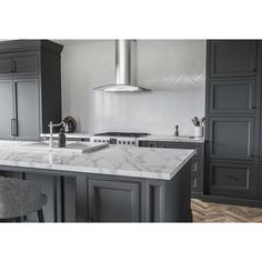 a large kitchen with marble counter tops and gray cabinetry, along with an island