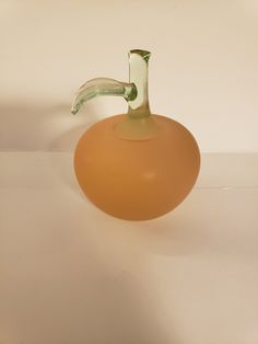 an orange glass vase with a curved handle