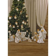 a christmas tree with white and gold ornaments in front of it is surrounded by other figurines