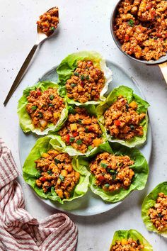 three lettuce cups filled with meat and vegetables next to a jar of sauce