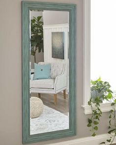 a mirror sitting on top of a wall next to a chair and potted plant