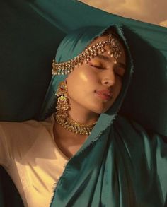 a woman in a green shawl with her eyes closed and head covered by jewelry