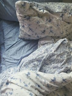 an unmade bed with blue and white sheets