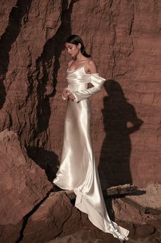 a woman in a white dress standing on rocks