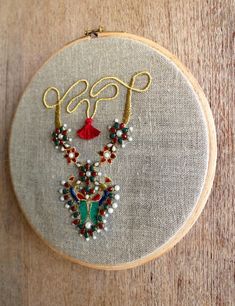 a close up of a embroidery on a wooden hoop with beads and tassels