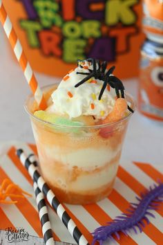 a halloween dessert with whipped cream and sprinkles in a glass on an orange striped place mat