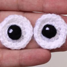 two crocheted eyes are shown in the palm of someone's hand