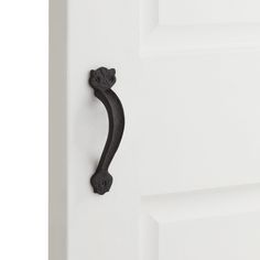 an iron door handle on a white door with a black cat head and paw design