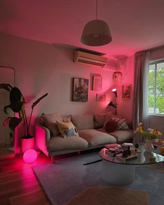 a living room filled with furniture and pink lighting