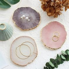 four different colored plates sitting on top of a white table next to flowers and greenery