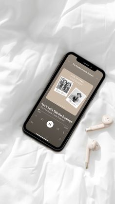 an iphone and ear buds laying on top of a white sheet with the music player app open