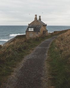 an old house on the side of a cliff by the ocean