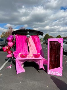 a pink table with balloons on it in a parking lot