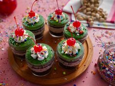 cupcakes with green frosting and sprinkles on a wooden plate