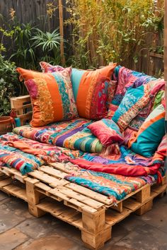 a couch made out of wooden pallets with colorful pillows on it and some plants in the background