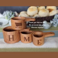 four wooden measuring cups with the word home engraved on them, sitting in front of some bread rolls