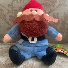 a stuffed toy with a red hat and beard sitting on a couch next to a book