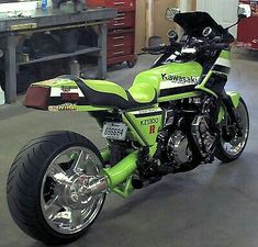 a green motorcycle parked in a garage next to a workbench with tools on it