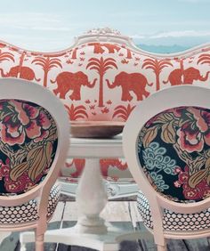 two chairs sitting next to each other on top of a wooden table with elephants painted on it