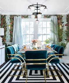 a dining room with blue velvet chairs and black and white striped rug on the floor