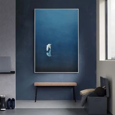 a painting hangs on the wall above a bench in a room with blue walls and flooring