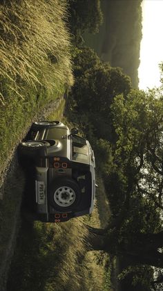 an aerial view of a truck driving down a road next to some trees and grass