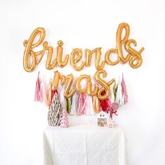 a white table topped with balloons that say friends and christmas trees on top of it